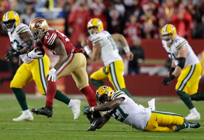 San Francisco 49ers linebacker Dre Greenlaw (57) eludes Green Bay Packers cornerback Zyon Gilbert (27) after intercepting a pass in the third quarter during their NFC divisional playoff football game Saturday, January 20, 2024, at Levi's Stadium in Santa Clara, California.