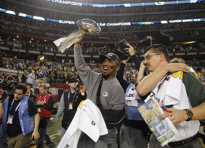 Charles Woodson (21) carries the Vince Lombardi Trophy as he walks around the field after the Packers' victory over the Steelers in Super Bowl XLV at Cowboys Stadium in Arlington, Texas, on Feb. 6, 2011.
