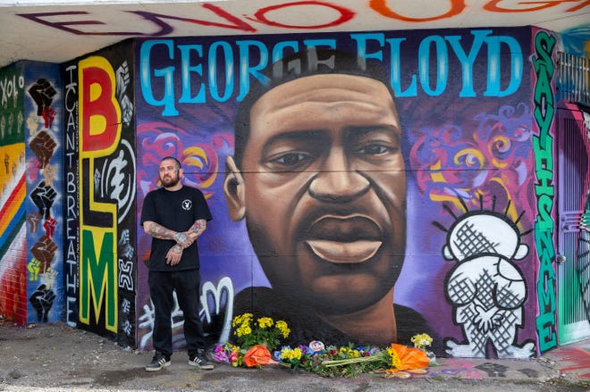 Artist Chris Burke stands in front of a new mural in memory of George Floyd at E. North Ave. and W. Holton St. Burke created the image of Floyd, with other artists contributing to the rest of the mural.