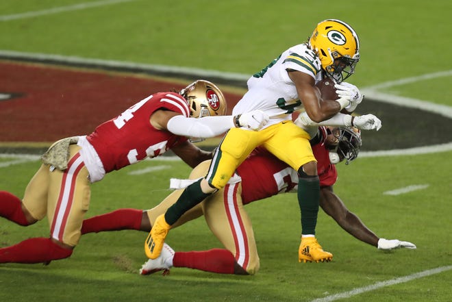 Green Bay Packers running back Aaron Jones, center, runs against San Francisco 49ers middle linebacker Fred Warner, left, and strong safety Jaquiski Tartt during the first half of an NFL football game in Santa Clara, Calif., Thursday, Nov. 5, 2020.