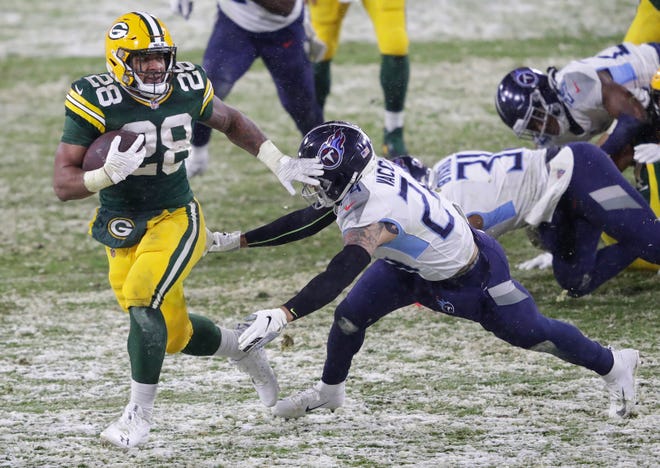 Green Bay Packers running back A.J. Dillon (28) breaks away from Tennessee Titans strong safety Kenny Vaccaro (24) for a touchdown run in the third quarter during their football game Sunday, December 27, 2020, at Lambeau Field in Green Bay, Wis.