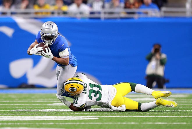 DETROIT, MICHIGAN - JANUARY 09: Adrian Amos of the Green Bay Packers tackles Kalif Raymond of the Detroit Lions after a reception during the first half at Ford Field on January 09, 2022 in Detroit, Michigan.