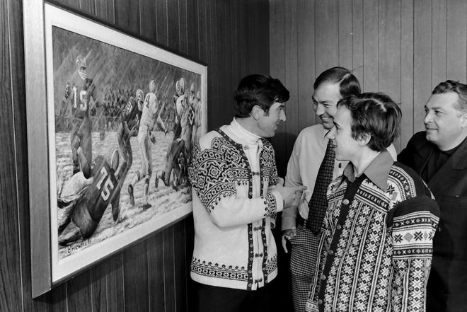 "That's you?" asked a surprised Gariy Napalkov, a Soviet Olympic ski jumper, when told that the #15 in painting on the wall was the same fellow he was talking to, Green Bay Packers head coach Bart Starr. With Napalkov is teammate Valdimir Frolov, second from right, and team leader Chota Chalaganidze, as they toured the Packers facility on Feb. 26, 1975, in Green Bay, Wis.