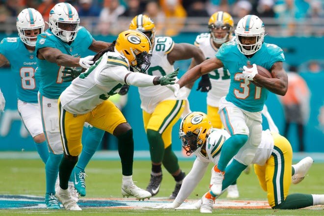 Miami Dolphins running back Raheem Mostert (31) runs ahead of Green Bay Packers defensive tackle Jonathan Ford (99) during the first quarter on Dec. 25, 2022, at Hard Rock Stadium.